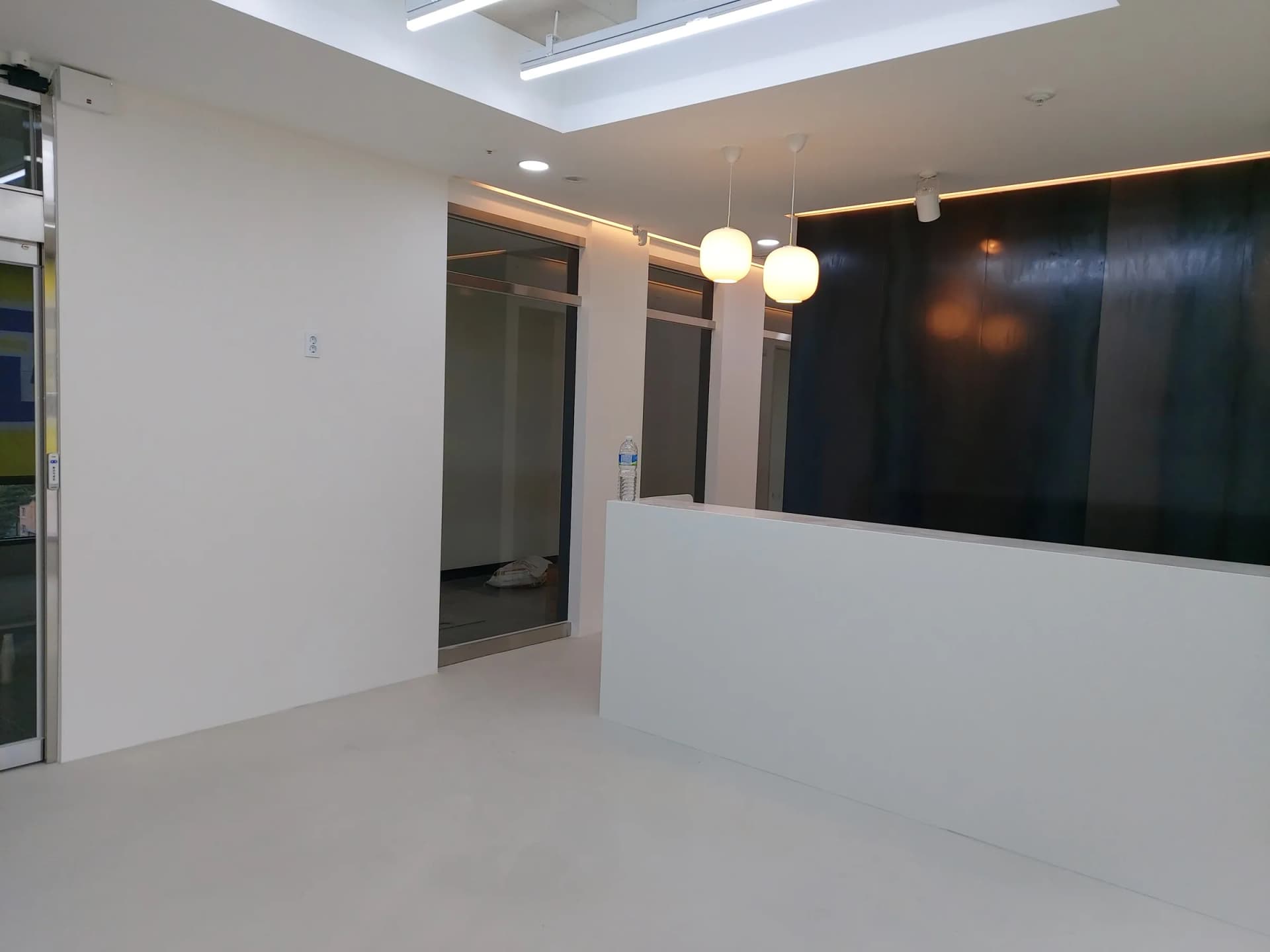 펜던트 조명과 짙은 금속 벽이 있는 의원 접수 카운터 구역