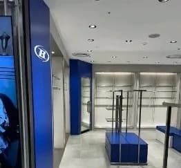 푸른색 마감 벽면과 금속 행거가 설치된 매장 입구