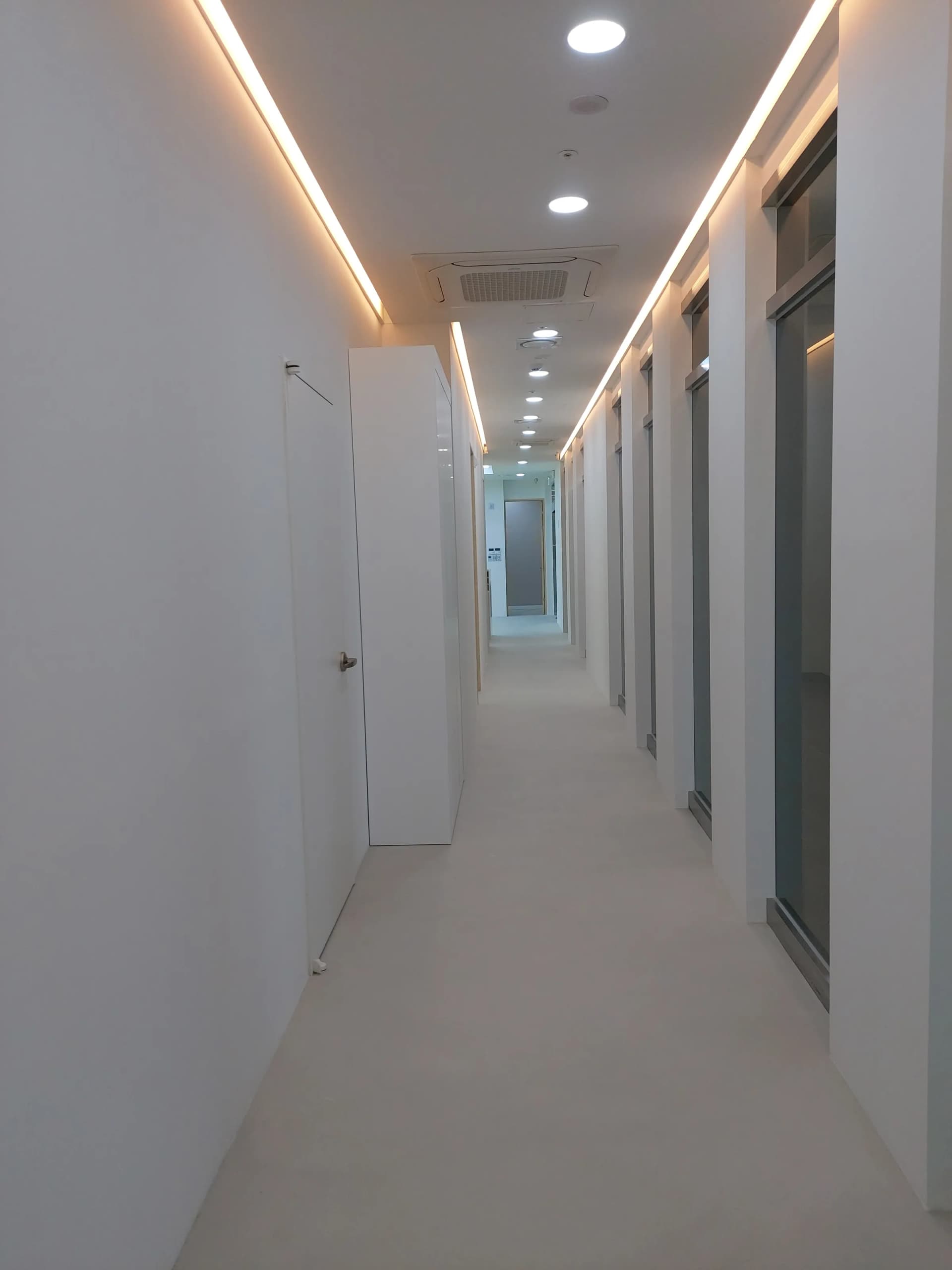 간접 조명이 설치된 흰색 의원 복도와 마감된 바닥
